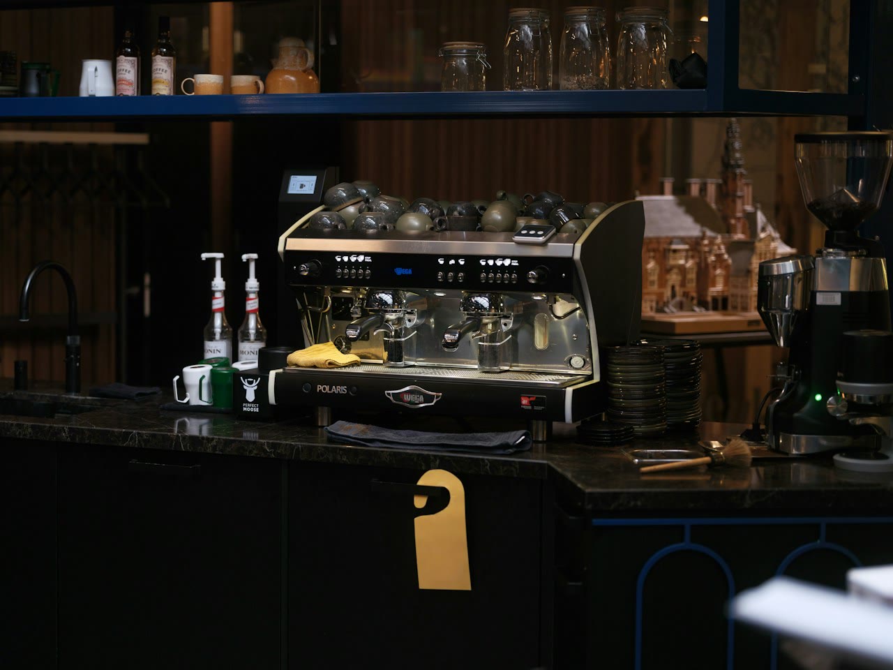 Fotografía ilustrativa de una barra de café y máquina de espresso; no corresponde al recinto